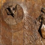 particolare del bassorilievo in bronzo sul portone della chiesa del Sacro Cuore. L'Annunciazione con la colomba a sinistra e Maria, sorpresa, sulla destra