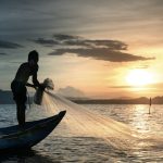 pescatore butta le reti dalla barca